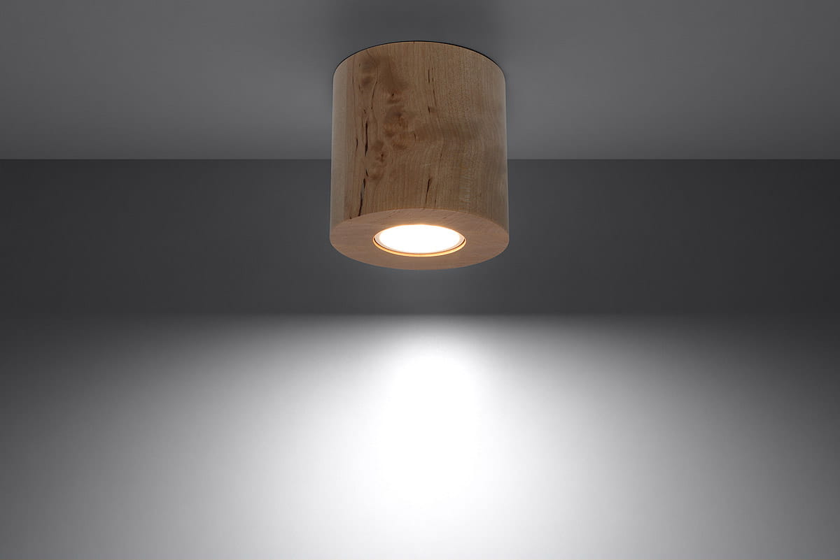Lampa sufitowa Orbis Drewno 1-punktowa SL.0492 w kształcie cylindrycznym, wykonana z jasnego drewna. Ujęcie z dołu, pokazujące źródło światła w środku. Tło w odcieniach szarości, podkreślające naturalny materiał.