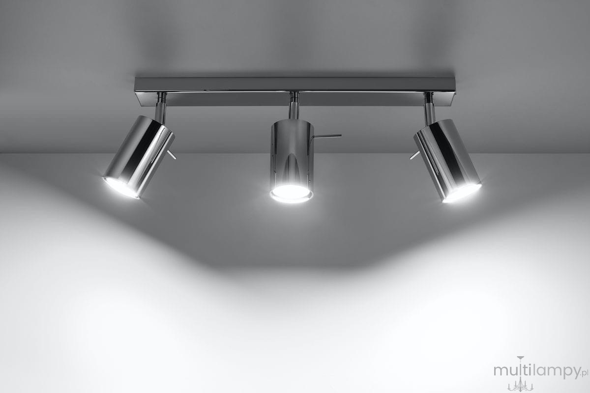 Lampa sufitowa 3-punktowa w chromowanym wykończeniu, z trzema cylindrycznymi reflektorami. Ujęcie z góry, pokazujące montaż na suficie oraz oświetlenie kierunkowe. Reflektory w pozycji ustawionej na różne kierunki. Tło proste, jasne.