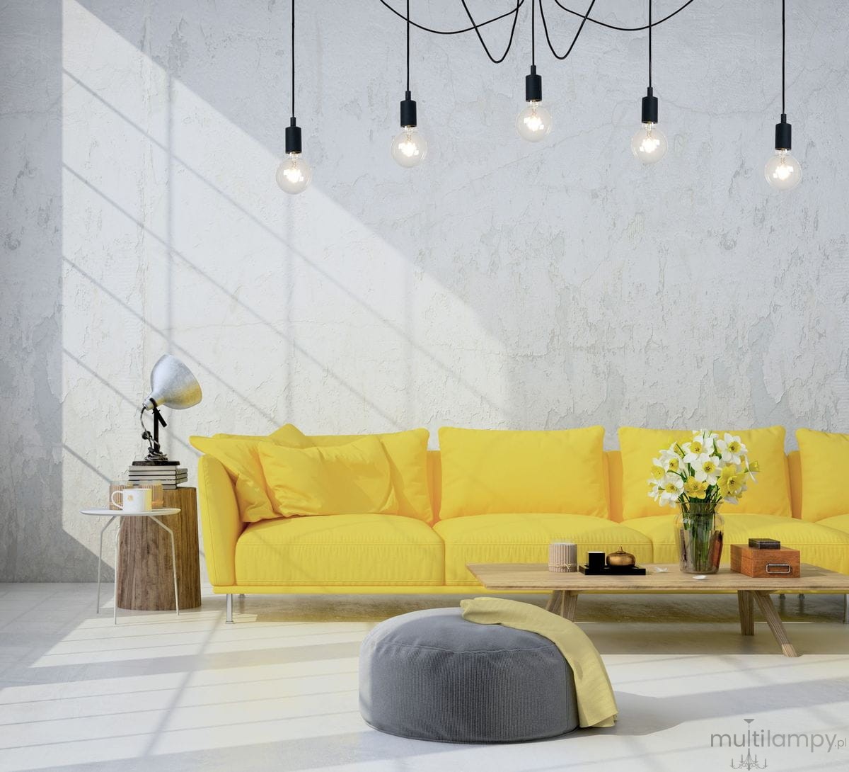 Lampa wisząca Fix Multiple z pięcioma punktami świetlnymi w czarnych oprawach, zawieszona na kablach w minimalistycznym wnętrzu. W tle żółta kanapa i stół z dekoracjami, jasne światło oświetla przestrzeń.