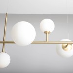 Lampa wisząca Dione 6-punktowa w kolorze mosiądzu, z białymi, okrągłymi kloszami z matowego szkła. Produkt zawieszony na cienkich linkach, z widocznym wykończeniem metalowym, w minimalistycznym stylu.