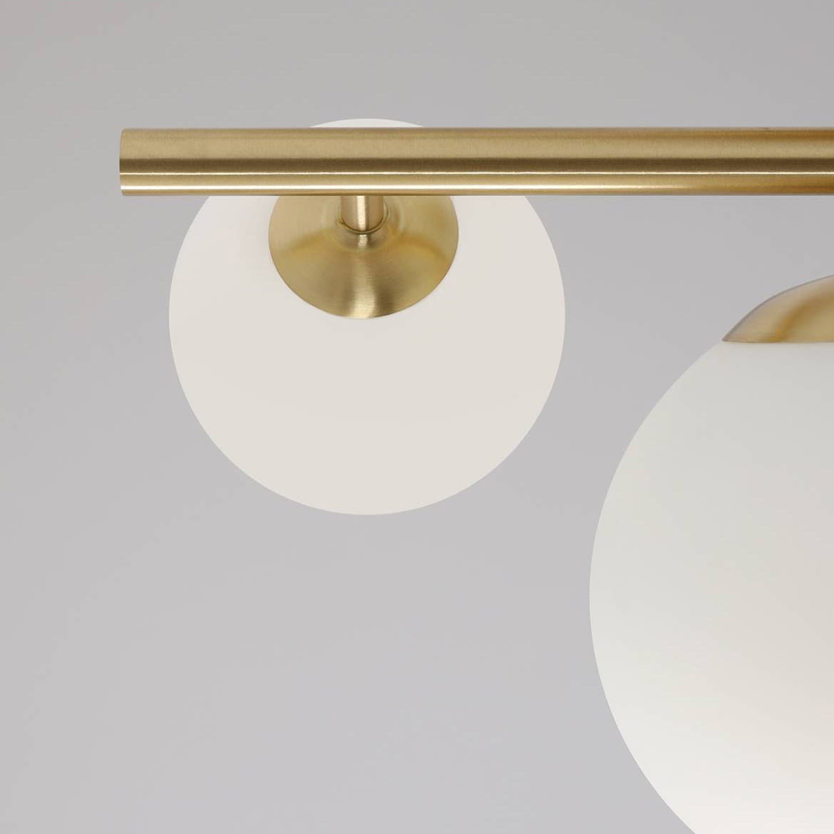 Lampa sufitowa Dione 3-punktowa, wykonana z mosiądzu, z białymi kloszami w kształcie półkul. Ujęcie z góry, pokazujące detal mocowania oraz gładką powierzchnię kloszy. Całość na jednolitym tle, podkreślająca minimalistyczny design.