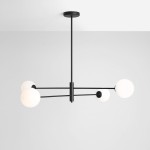 Lampa wisząca Homme czarna z czterema okrągłymi kloszami w białym kolorze, zawieszona na cienkich metalowych prętach, umieszczona na jasnym tle. Klosze równomiernie rozmieszczone, w formie prostokątnej konstrukcji.