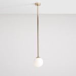 Złota lampa wisząca Pinne Long z jednym punktem świetlnym, z oprawą w formie długiego, metalowego pręta i okrągłym, białym kloszem. Produkt zawieszony na jasnym tle, w pozycji pionowej.