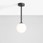 Czarna lampa wisząca Pinne Short z jednym punktem świetlnym, z okrągłym, białym kloszem. Produkt zawieszony na długim, prostym ramieniu, montowany do sufitu. Tło w jasnoszarym kolorze, minimalistyczna aranżacja.