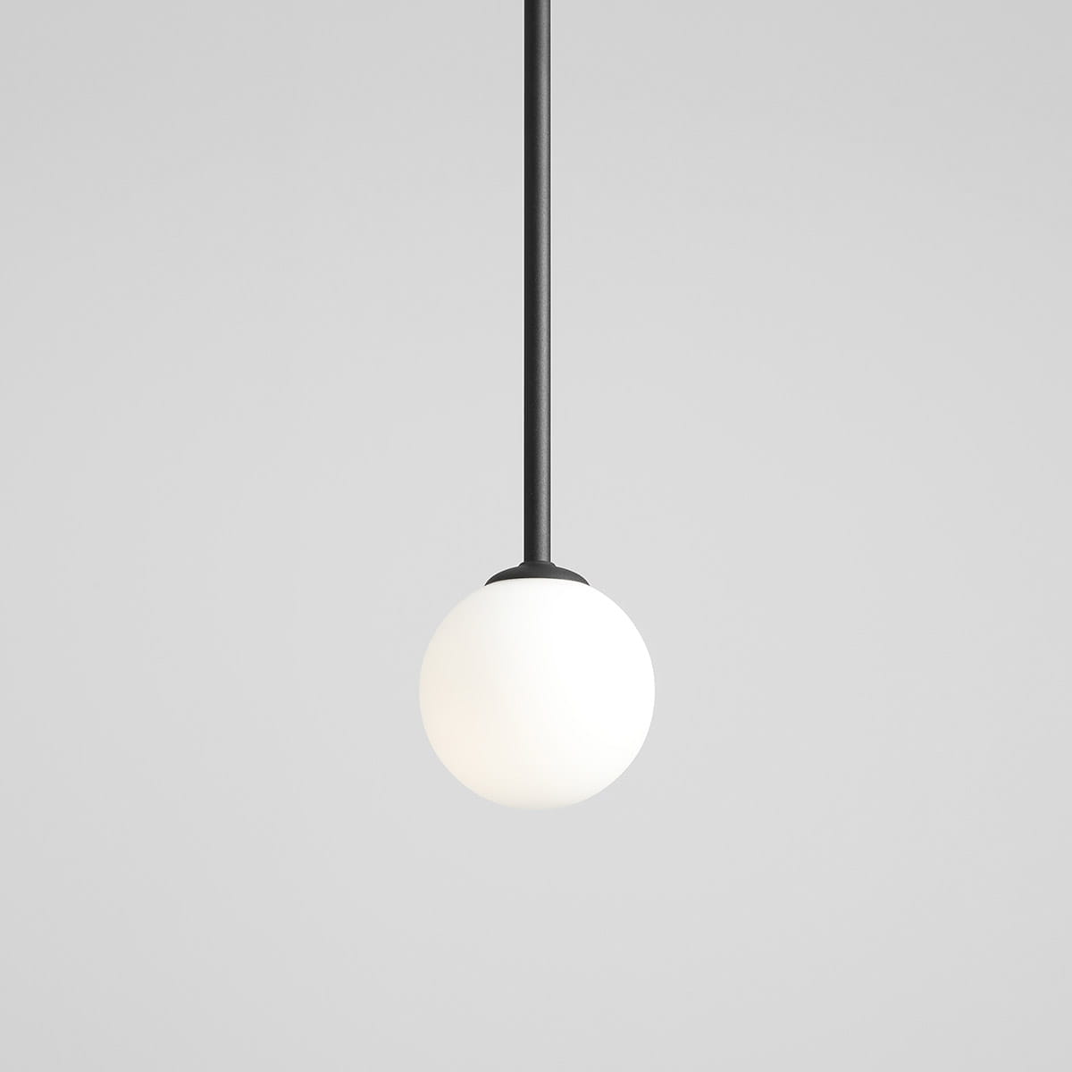 Czarna lampa wisząca Pinne Long z jednym punktem świetlnym, z długim, prostym ramieniem i okrągłą, matową białą kulą na dole. Produkt zawieszony na gładkim tle, podkreślający minimalistyczny design.