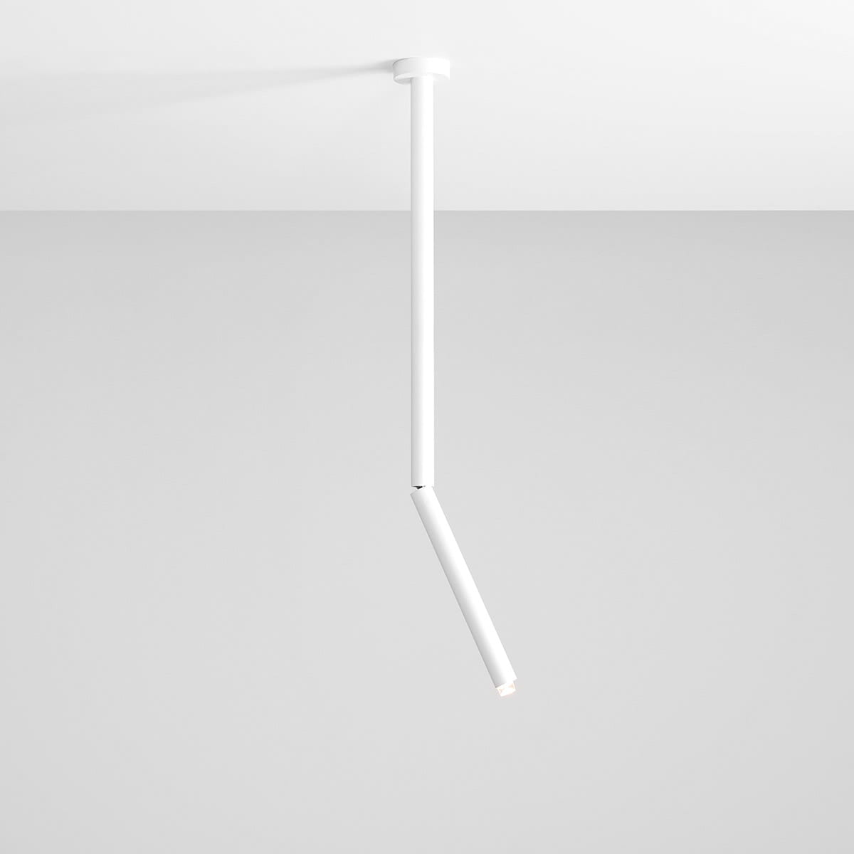 Lampa sufitowa Stick M w kolorze białym, jednopunktowa, z prostą, cylindryczną konstrukcją. Ujęcie z dołu, pokazujące wiszący element z wbudowanym źródłem światła, zamontowany na gładkim suficie. Tło w jasnoszarym kolorze.