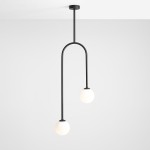 Lampa wisząca Nave w kolorze czarnym, 2-punktowa, z metalowym stelażem i dwoma okrągłymi, białymi kloszami. Ułożona w pozycji wiszącej, zawieszona na prostym, cylindrycznym wsporniku. Tło proste, jasne.