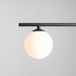 Czarna lampa wisząca Beryl Glass z trzema punktami świetlnymi, z matowym białym kloszem w kształcie kuli, zawieszona na prostym, czarnym stelażu. Ujęcie z boku, na szarym tle, podkreślające minimalistyczny design.