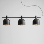 Czarna lampa wisząca Beryl z trzema punktami świetlnymi. Metalowe klosze o kształcie półkulistym, zawieszone na prostym, poziomym wsporniku. Lampa zawieszona na cienkim przewodzie na jasnym tle.