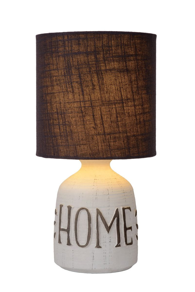 Lampa stołowa Cosby 1-punktowa z białą, ceramiczną podstawą z napisem HOME oraz ciemnobrązowym, tekstylnym kloszem. Ujęcie frontalne, lampa stoi na płaskiej powierzchni, emitując ciepłe światło.
