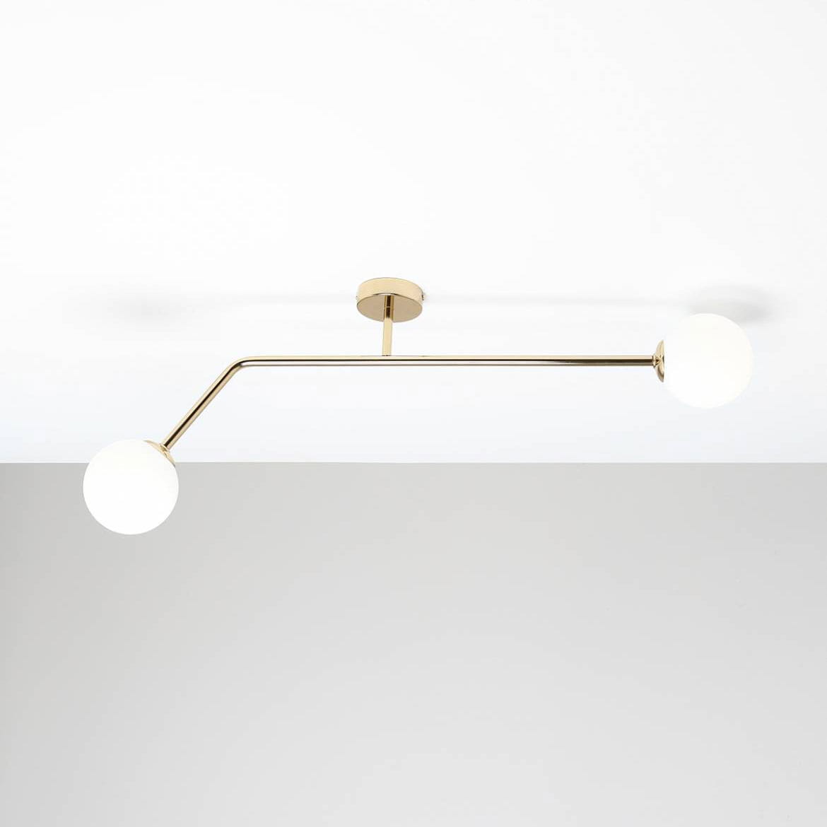 Lampa sufitowa Pure 2-punktowa w kolorze złotym, z prostą, metalową konstrukcją i dwoma okrągłymi, białymi kloszami. Ujęcie z góry, pokazujące lampę zamontowaną na suficie.