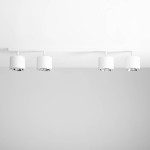 Lampa sufitowa 4-punktowa w kolorze białym z metalowymi reflektorami, zamontowana na prostokątnej listwie, w układzie równoległym. Ujęcie frontalne, na jednolitym tle.