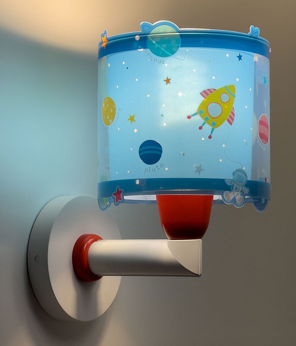 Kinkiet Planety z kolorowym abażurem w niebieskie wzory planet i rakiety, zamontowany na okrągłej, metalowej podstawie. Abażur z przezroczystego materiału, z czerwonym mocowaniem, świeci delikatnym światłem, tworząc przyjemny klimat.