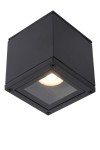 Czarna lampa sufitowa Aven IP65, 1-punktowa, w kształcie sześcianu. Ujęcie z góry z widocznym przezroczystym kloszem, w którym znajduje się okrągła żarówka. W metalowej obudowie widoczne są cztery mocowania. Idealna do wnętrz i na zewnątrz.