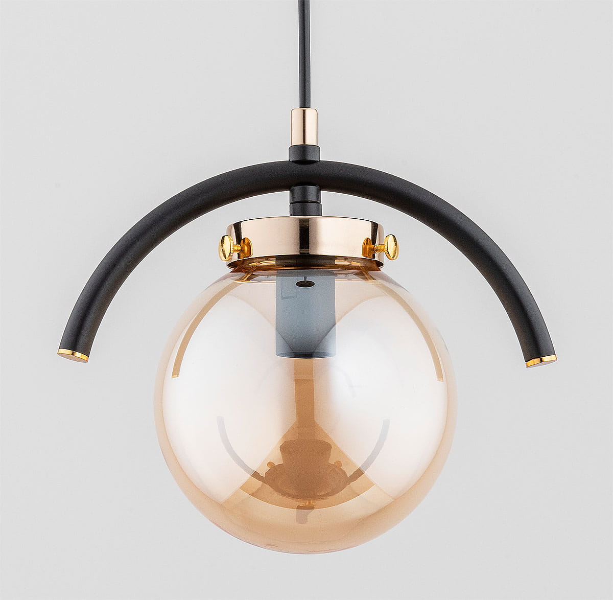 Lampa wisząca Korda 1-punktowa w złotym kolorze, z okrągłym kloszem w odcieniu brązowym. Metalowy stelaż w czerni z ozdobnymi złotymi detalami. Ujęcie frontalne, lampa zawieszona na cienkim kablu, prezentuje elegancki design.