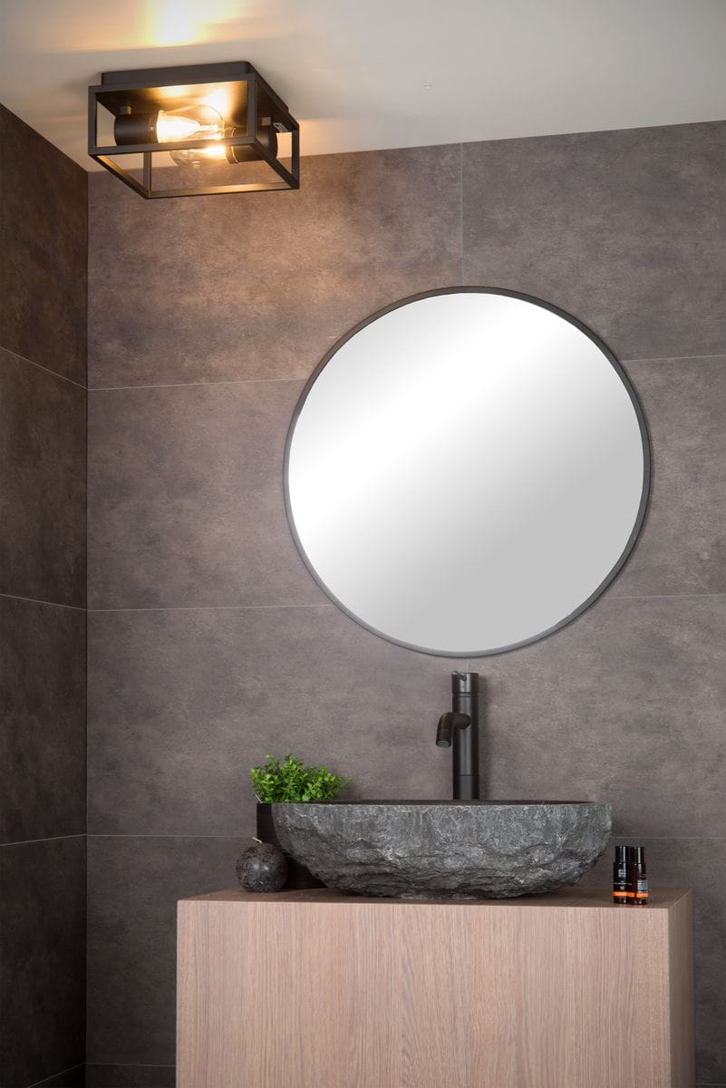 Carlyn IP54 lampa sufitowa 2-punktowa w kolorze czarnym, zamontowana na suficie, z widocznymi żarówkami. W tle okrągłe lustro i kamienna umywalka na drewnianym blacie w nowoczesnej aranżacji łazienki.