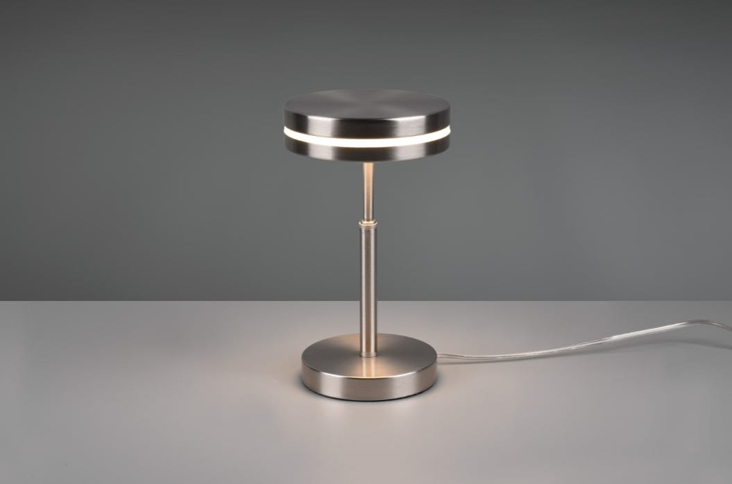Lampa stołowa Franklin LED 1-punktowa w kolorze matowego niklu. Okrągła podstawa i klosz z wbudowanym źródłem światła, umieszczona na smukłym stelażu. Widoczny przewód zasilający. Ujęcie frontalne na jednolitym tle.