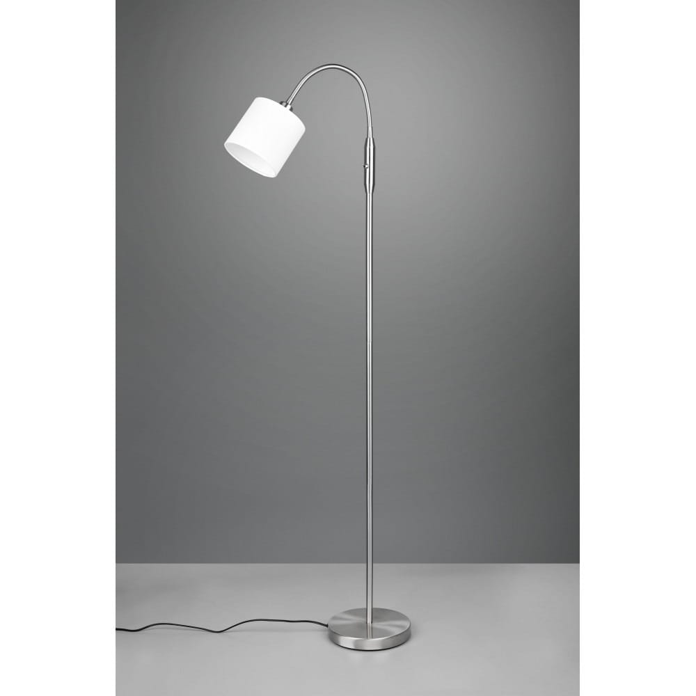 Lampa podłogowa Tommy 1-punktowa w kolorze niklu, z białym kloszem. Stojąca konstrukcja z lekko wygiętym ramieniem, umieszczona na okrągłej podstawie. Widoczny kabel zasilający. Tło w odcieniach szarości.