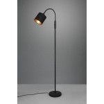 Lampa podłogowa Tommy w kolorze czarnym, z jednopunktowym źródłem światła. Posiada długą, prostą podstawę oraz zaokrągloną głowicę, która jest lekko nachylona. Kabel z włącznikiem widoczny obok podstawy. Tło w odcieniach szarości.