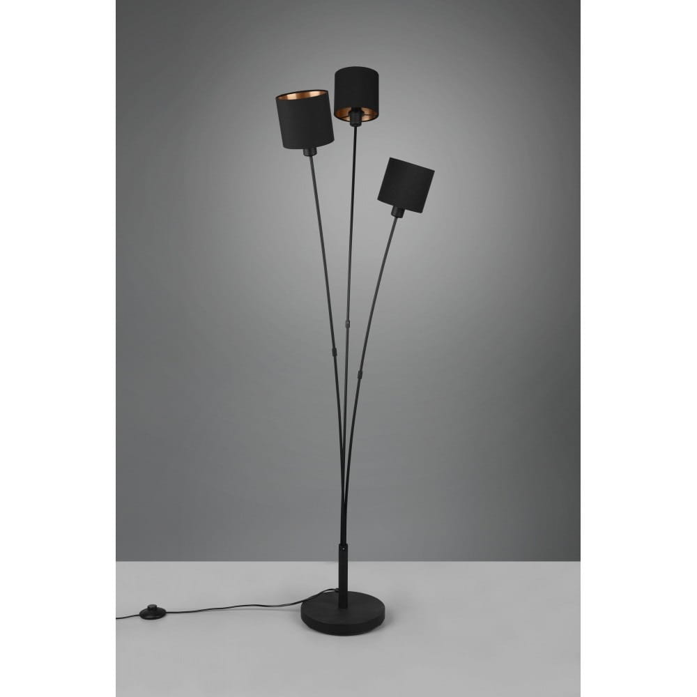 Czarna lampa podłogowa 3-punktowa Tommy z trzema cylindrycznymi kloszami, wyposażona w smukłe, metalowe ramiona. Ustawiona na okrągłej podstawie, z widocznym przewodem z włącznikiem. Tło w odcieniach szarości.