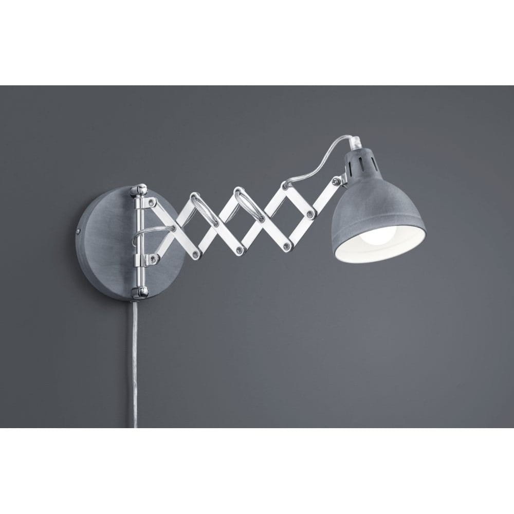 Kinkiet Scissor w kolorze szarym z chromowanym ramieniem, stylizowany na scyzoryk. Lampa ma okrągłą podstawę, elastyczne ramię i klosz, który skierowany jest w dół. Wtyczka na przewodzie zasilającym widoczna z boku. Tło szare.