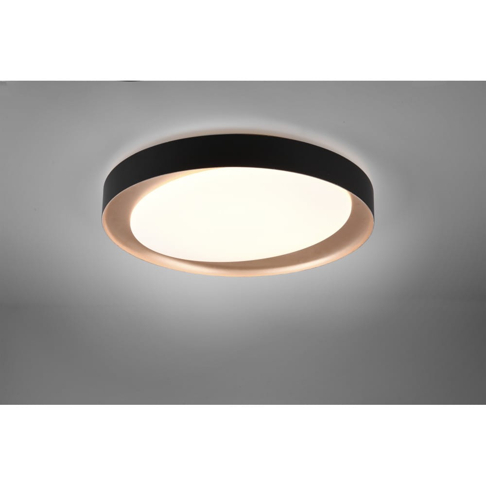 Plafon Zeta D48 LED w kolorze czarnym, okrągły, z białym, matowym kloszem. Zainstalowany na suficie, z delikatnym podświetleniem. Produkt z pilotem do zdalnego sterowania.