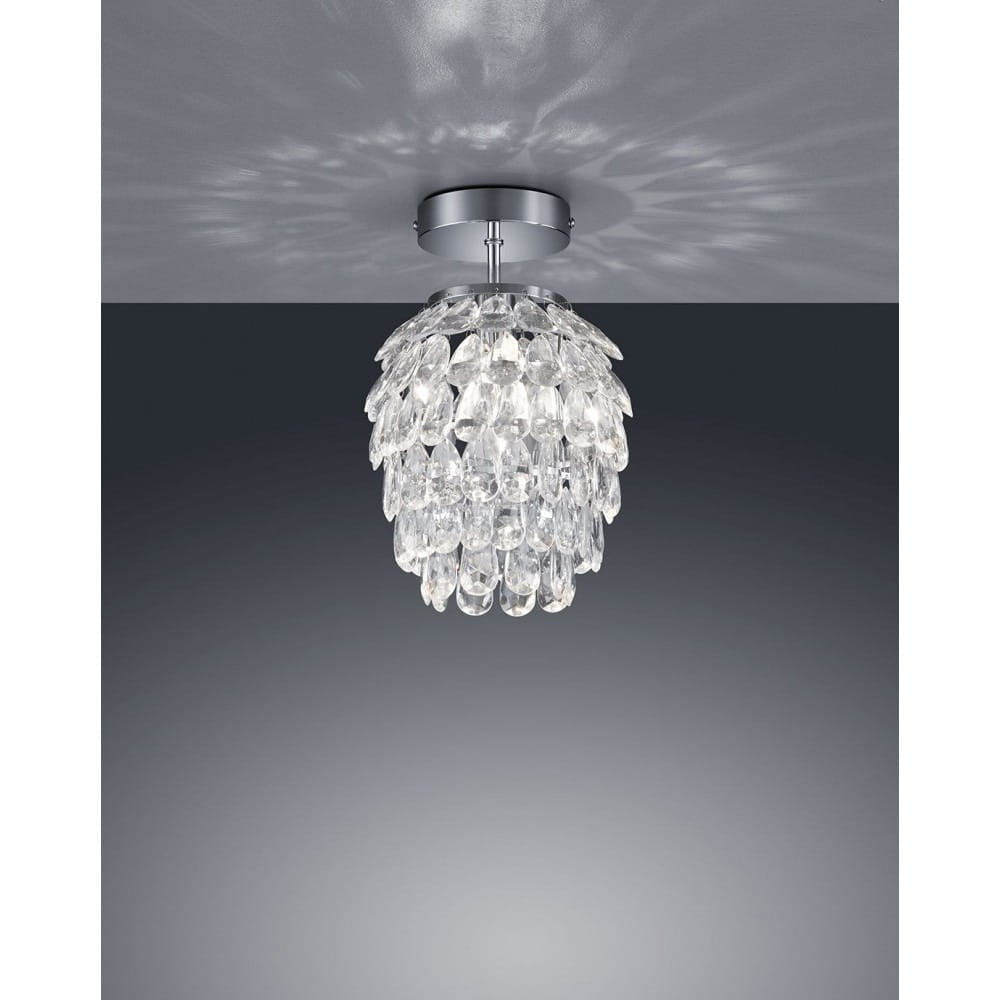 Lampa sufitowa Petty D20 w kolorze chromu, z przezroczystymi kryształowymi elementami, o zaokrąglonym kształcie. Zawieszona pod sufitem, emituje delikatne światło, tworząc atrakcyjne refleksy na tle.