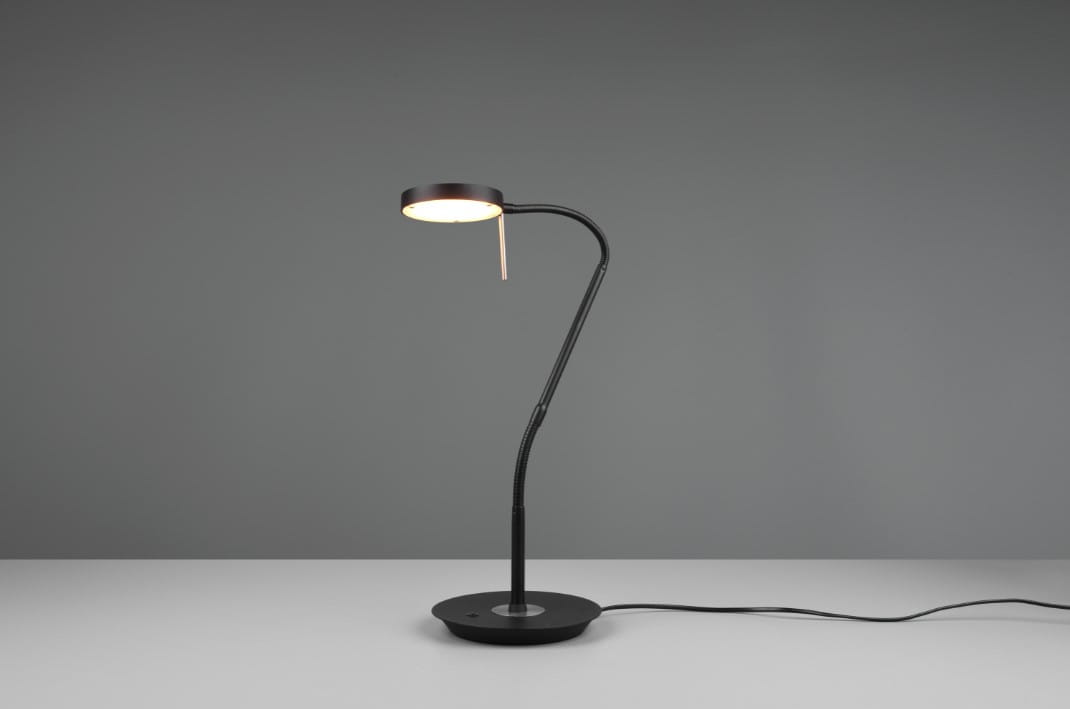 Czarna lampka biurkowa Monza LED z elastycznym ramieniem i okrągłą podstawą. Ujęcie frontalne, lampa w pozycji stojącej, świecąca z okrągłym kloszem. Prosty, nowoczesny design na szarym tle.