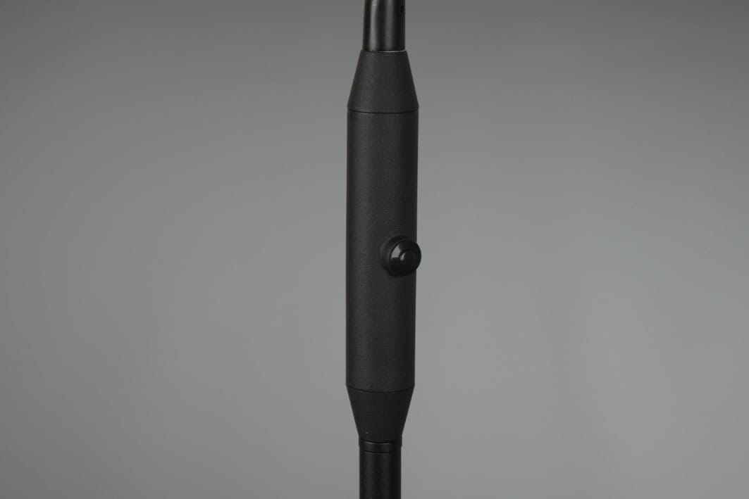 Czarna lampa podłogowa Monza LED z widocznym włącznikiem. Produkt ma smukłą, cylindryczną konstrukcję, z gładką powierzchnią. Ujęcie z boku pokazuje detale włącznika na obudowie, co podkreśla funkcjonalność lampy.