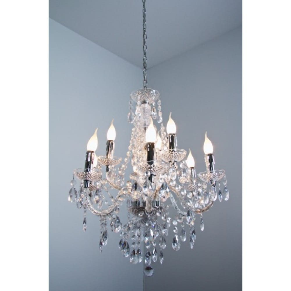 Luster żyrandol 9-punktowy, transparentny, z chromowanymi elementami, osiem źródeł światła z dekoracyjnymi kloszami, bogato zdobiony kryształkami, zwisający na łańcuchu, na jednolitym tle.