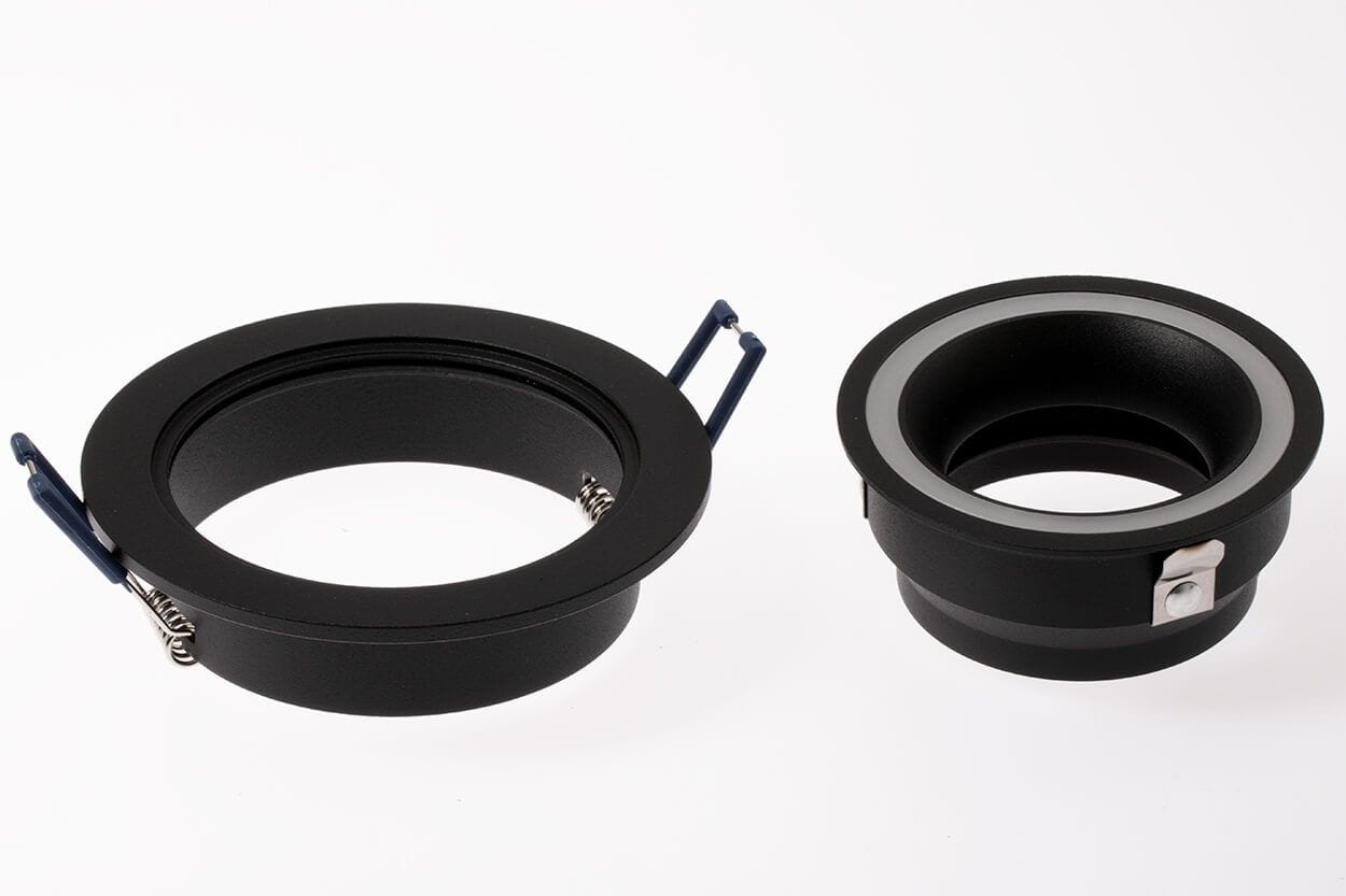 Okrągła oprawa oczko do zabudowy GU10 w kolorze czarnym, wykonana z metalu. Widoczne dwa elementy: większy z sprężynkami mocującymi, mniejszy z metalowym mocowaniem. Ujęcie frontalne na białym tle, ukazujące detale konstrukcyjne.