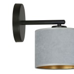 Kinkiet Hilde 1-punktowy w kolorze szarym z okrągłą podstawą w kolorze czarnym. Lampa zawiera materiałowy klosz o matowej fakturze, z wewnętrzną złotą powłoką, zamontowana na krótkim ramieniu.