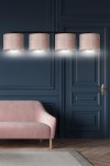 Lampa wisząca Hilde 4-punktowa w kolorze różowym, z czterema okrągłymi kloszami zawieszonymi na czarnym stelażu. Ujęcie frontalne, lampa umieszczona nad różową sofą na tle granatowej ściany. Klosze emitują ciepłe światło.