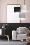 Lampa wisząca Hilde 3-punktowa w kolorach czarnym, szarym i kremowym, z okrągłymi kloszami wykonanymi z materiału, zawieszona na cienkich linkach. W tle minimalistyczna aranżacja salonu z jasną sofą i ciemną ścianą.