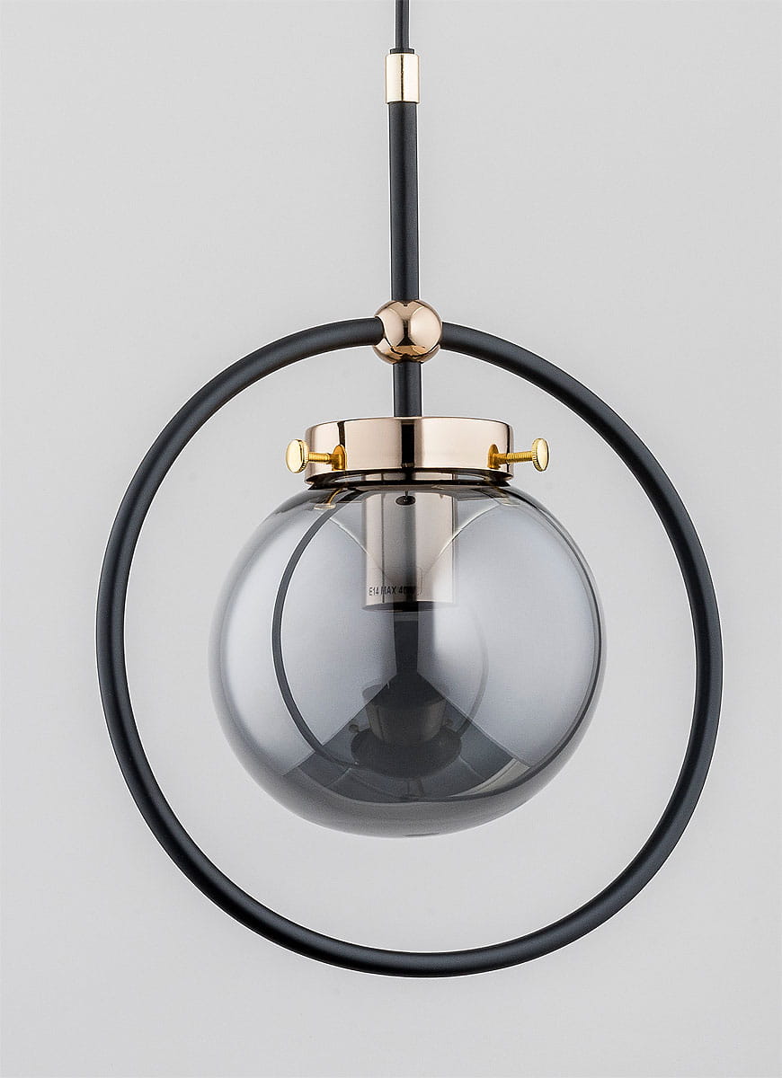 Czarna lampa wisząca Akira z metalowym złotym detalem. Okrągła oprawa z ciemnoszarego szkła zawieszona na cienkim czarnym kablu. W komplecie z okrągłym pierścieniem, prezentująca nowoczesny design. Ujęcie frontalne, na jednolitym tle.