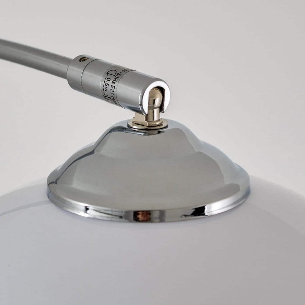 Lampa podłogowa Brasilia z chromowanym wykończeniem. Widoczna metalowa podstawa z zaokrąglonym kształtem oraz chromowanym elementem łączącym z przewodem. Stylowy detal, który łączy funkcjonalność z elegancją.