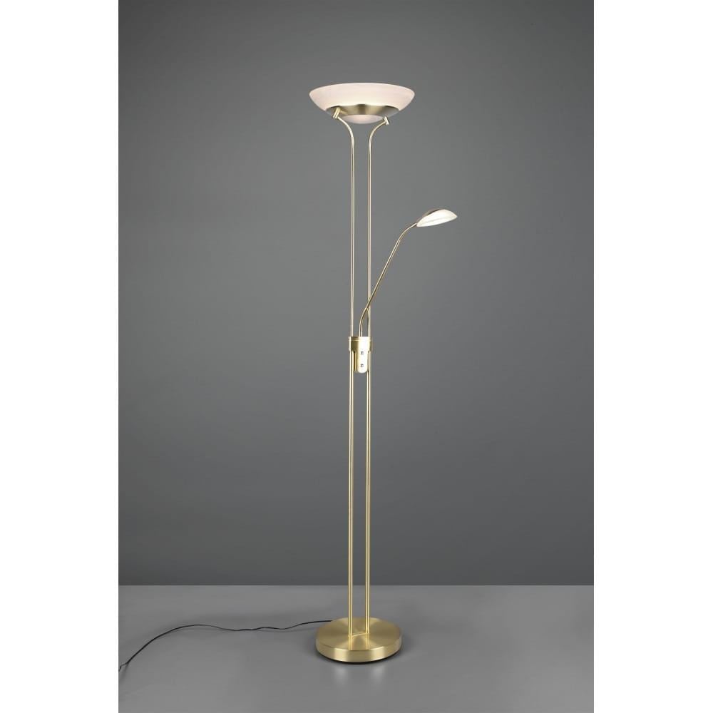Orson LED lampa podłogowa 2-punktowa w kolorze mosiądzu, z dużą okrągłą górną osłoną oraz regulowanym ramieniem. Stojąca na okrągłej podstawie, z widocznym przewodem. Tło w odcieniach szarości, co podkreśla elegancki wygląd lampy.