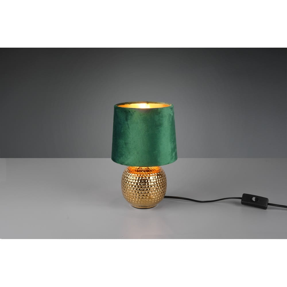 Lampa stołowa Sophia 1-punktowa z zielonym, welurowym abażurem na złotej, teksturowanej podstawie. Produkt stoi na płaskiej powierzchni, z widocznym przewodem z włącznikiem. Tło szare, neutralne.