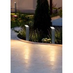 Lampa stojąca ogrodowa Pearl H50 LED w antracytowym kolorze, z prostokątnym korpusem, umieszczona na ścieżce otoczonej kwiatami. Kąt ujęcia z boku, pokazujący delikatne oświetlenie otoczenia. W tle widoczna zieleń i kamienna nawierzchnia.