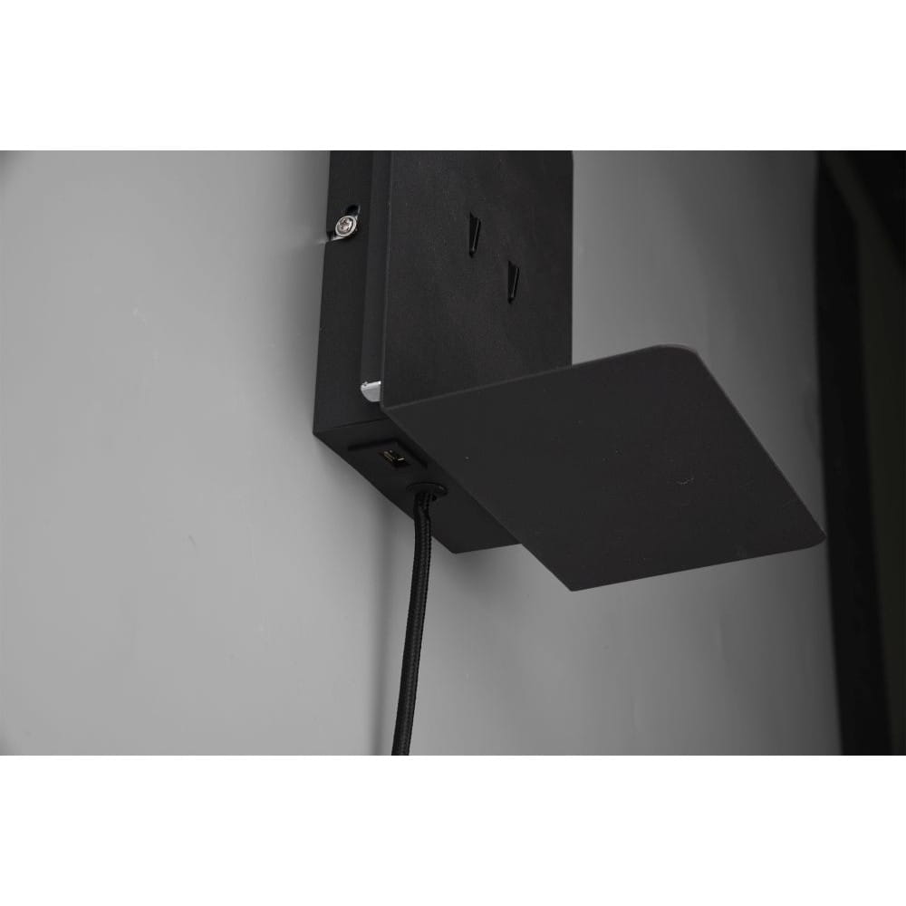 Czarny kinkiet LED z portem USB, zamontowany na ścianie. Z widoczną półką na drobne przedmioty. Kąt ujęcia z boku, ukazujący kabel zasilający oraz uchwyt do montażu. Prosta, minimalistyczna konstrukcja, matowe wykończenie.