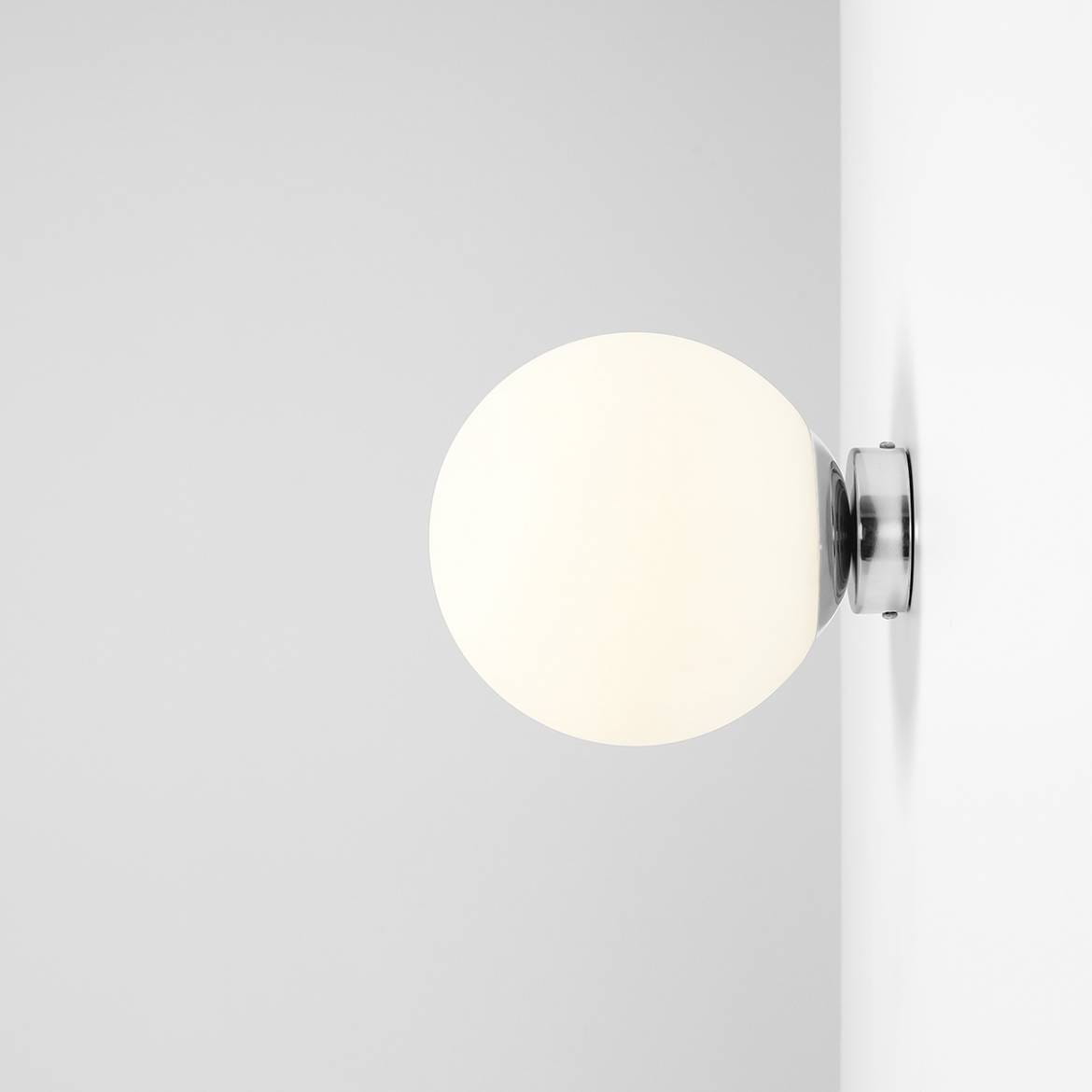 Kinkiet Ball D20 w kolorze chromu, z półkulistym kloszem w odcieniu białym. Zainstalowany na ścianie, widoczny z boku. Prosty design, idealny do nowoczesnych wnętrz.