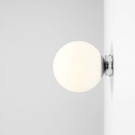 Kinkiet Ball D20 w kolorze chromu, z półkulistym kloszem w odcieniu białym. Zainstalowany na ścianie, widoczny z boku. Prosty design, idealny do nowoczesnych wnętrz.