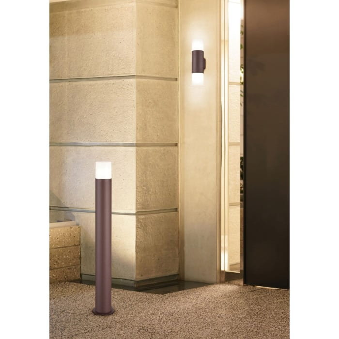Lampa stojąca ogrodowa Hoosic H80 w kolorze miedzi z białym kloszem, cylindryczna, ustawiona na podłodze w nowoczesnym wnętrzu. W tle widoczna gładka ściana i drzwi, co tworzy elegancki kontekst aranżacyjny.