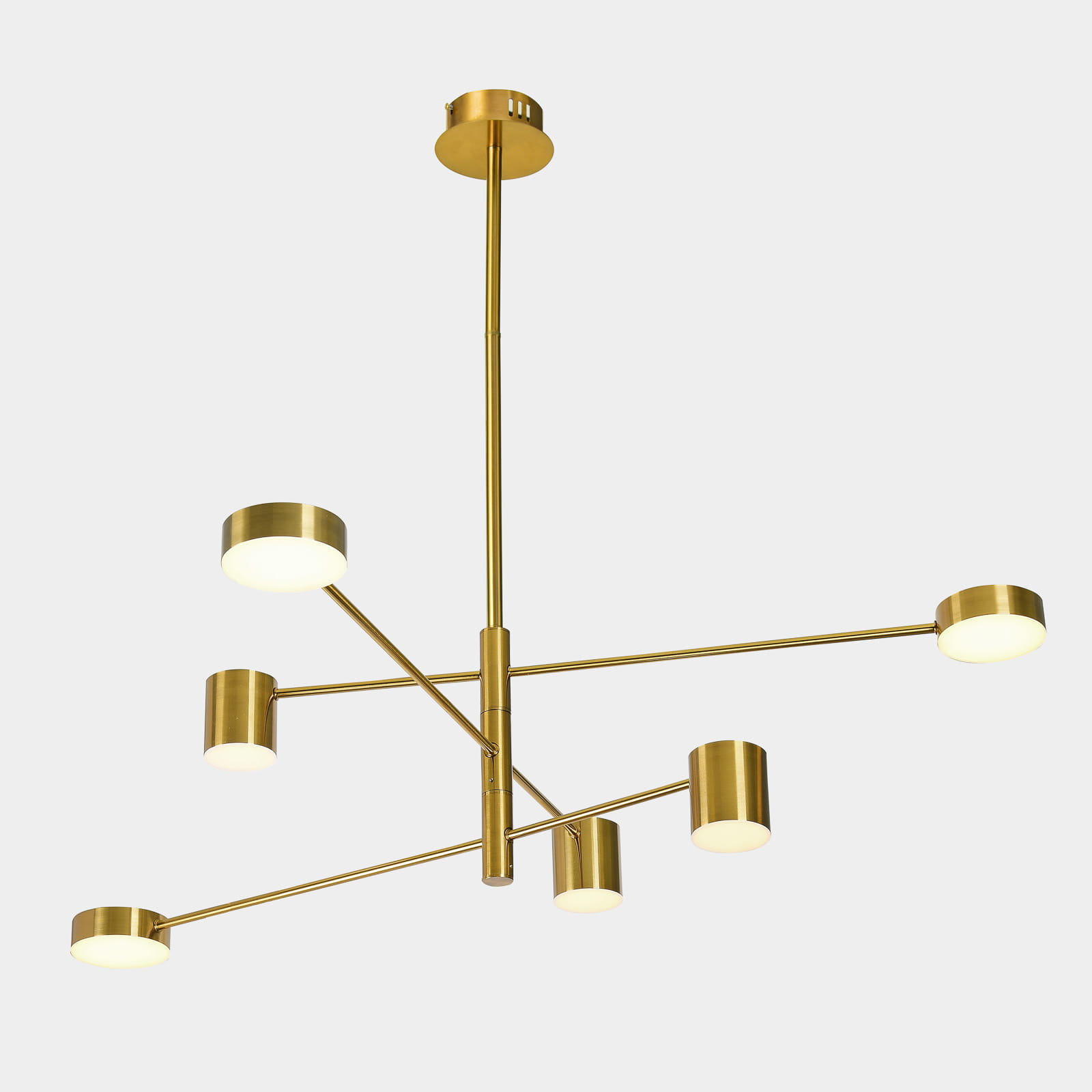 Złota lampa wisząca Remdal z sześcioma punktami świetlnymi, o minimalistycznym designie. Kąt ujęcia frontalny, lampa zawieszona na długim stelażu. Gładkie, matowe klosze w kształcie cylindrów, umieszczone na ramionach w różnych kierunkach.