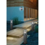 Lampa ogrodowa stojąca Garonne H80 w kolorze antracytowym, z minimalistycznym, prostokątnym kształtem. Umieszczona na drewnianym tarasie, oświetla ścieżkę. W tle widoczna jasna elewacja budynku oraz roślinność.