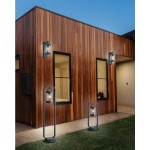 Lampa ogrodowa stojąca Sambesi H60 w kolorze antracytowym, z czujnikiem zmierzchu. Produkt ma prostokątną podstawę i szklany klosz, umieszczony na smukłej konstrukcji. Zastosowana w aranżacji przy drewnianej elewacji budynku, na trawie.