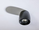 Rotondo lampa sufitowa kierunkowa w kolorze czarnym, o zaokrąglonym kształcie. Ujęcie z góry, pokazujące reflektor z widocznym wnętrzem. Lampa montowana do sufitu, z delikatnym cieniem na tle.
