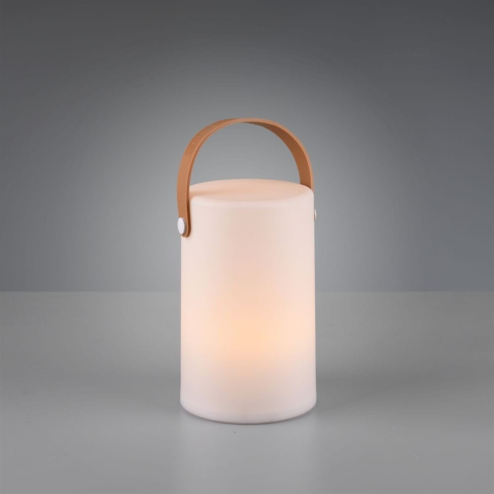 Biała lampa stołowa ogrodowa Aruba LED, cylindryczna, z jasnego materiału. Posiada skórzany uchwyt w kolorze brązowym. Lampa emituje ciepłe światło, ustawiona na szarej powierzchni, w prostym tle. Idealna do użytku na zewnątrz.