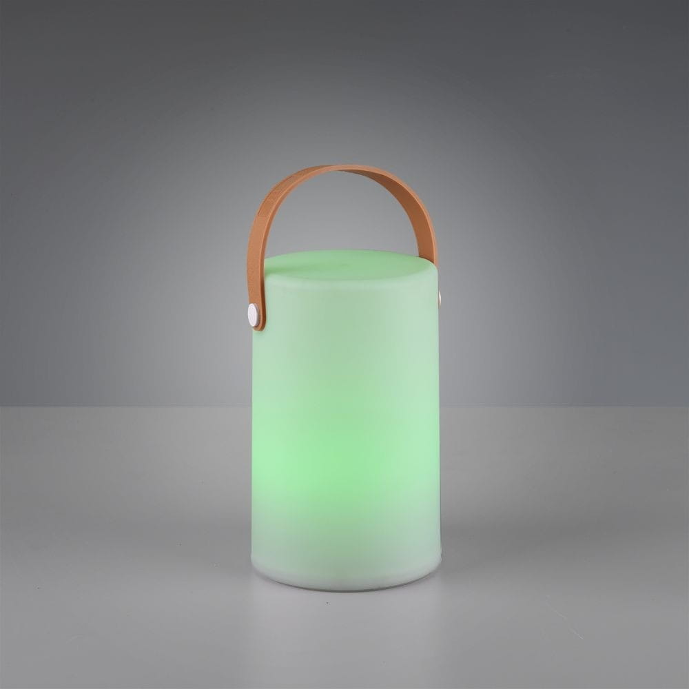 Biała lampa stołowa ogrodowa Aruba LED w kształcie cylindrycznym. Posiada skórzany uchwyt w kolorze brązowym. Świeci zielonym światłem, wykonana z matowego materiału. Stoi na płaskiej powierzchni, w tle szare.