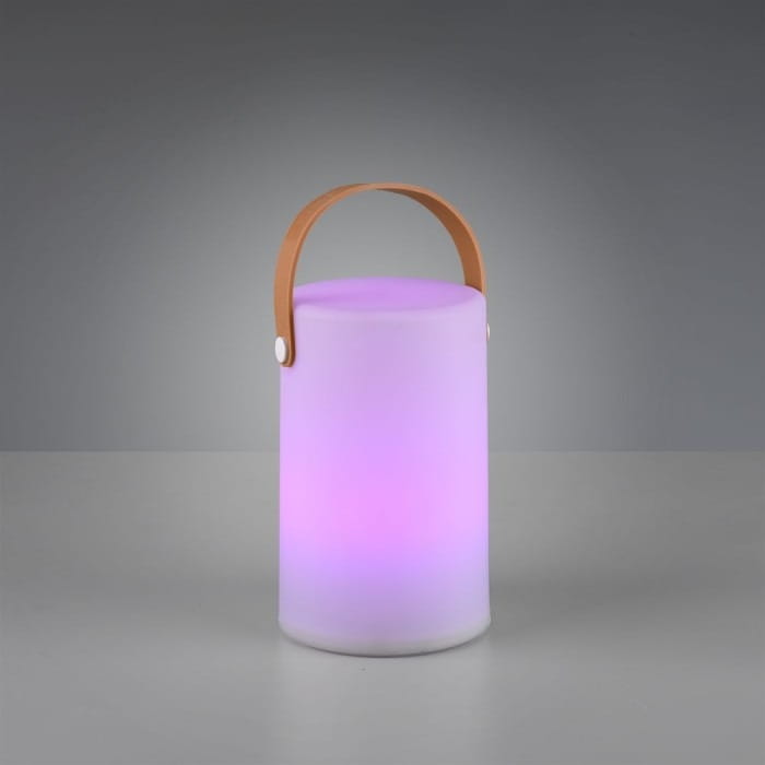 Lampa stołowa ogrodowa Aruba LED w białym kolorze, cylindryczna, z brązowym uchwytem. Emituje delikatne, zmieniające się kolory światło, umieszczona na szarej powierzchni. Idealna do użytku na zewnątrz.